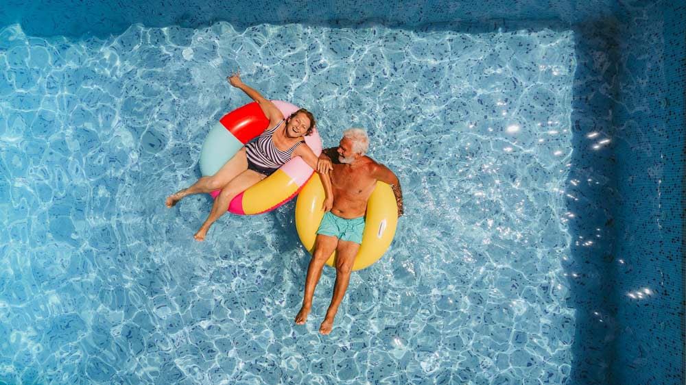 Older couple laying in their pool smiling